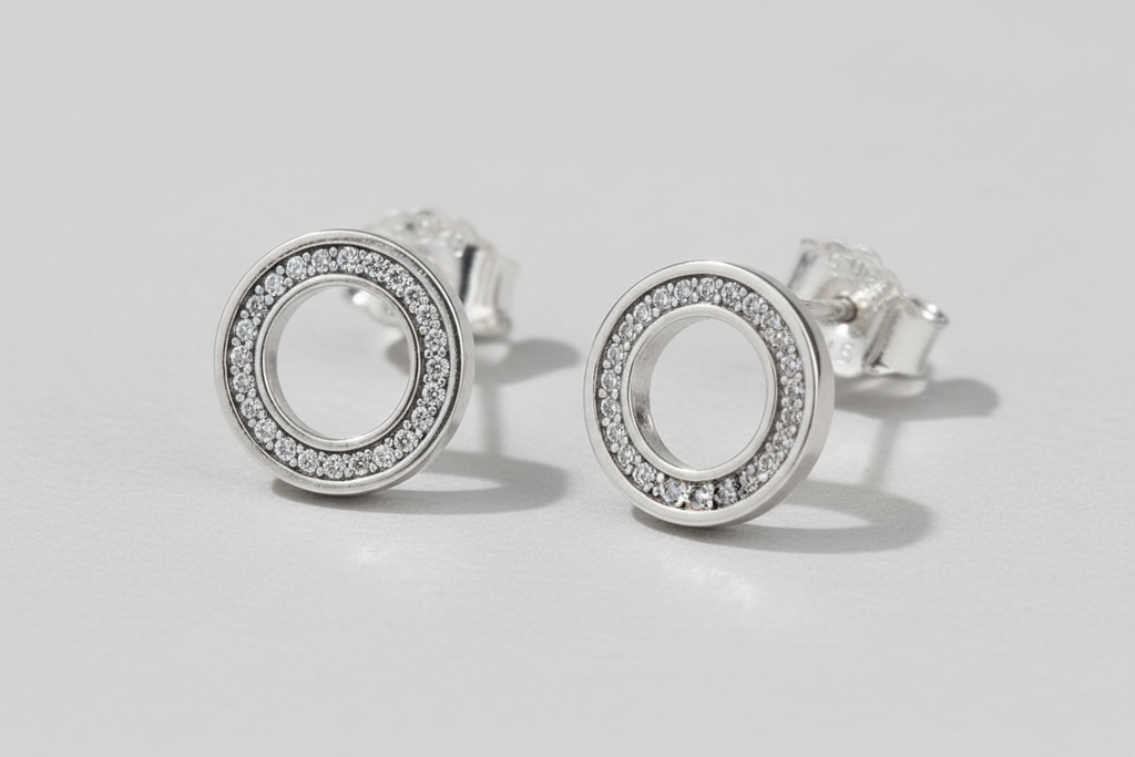 Silver circular earrings with clear stones on a blue background