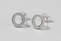 Silver circular earrings with clear stones on a blue background