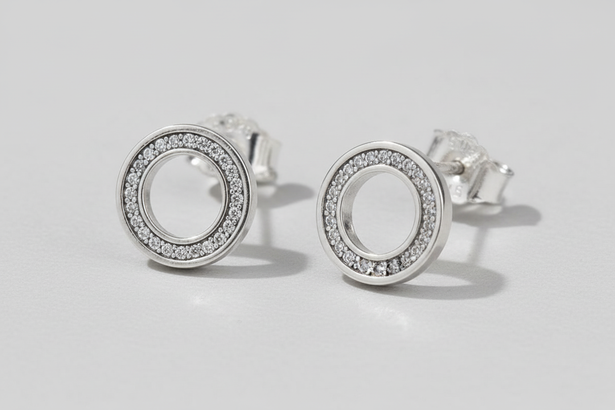 Silver circular earrings with clear stones on a blue background