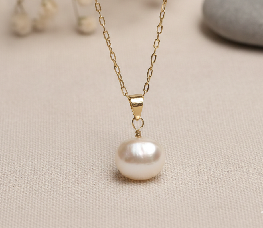 Pearl necklace with gold chain on a beige fabric background