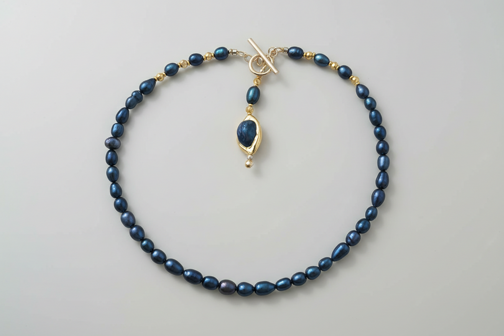 Blue beaded necklace with a gold clasp on a light gray background