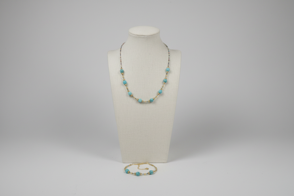 Necklace with turquoise beads on a mannequin bust against a gray background