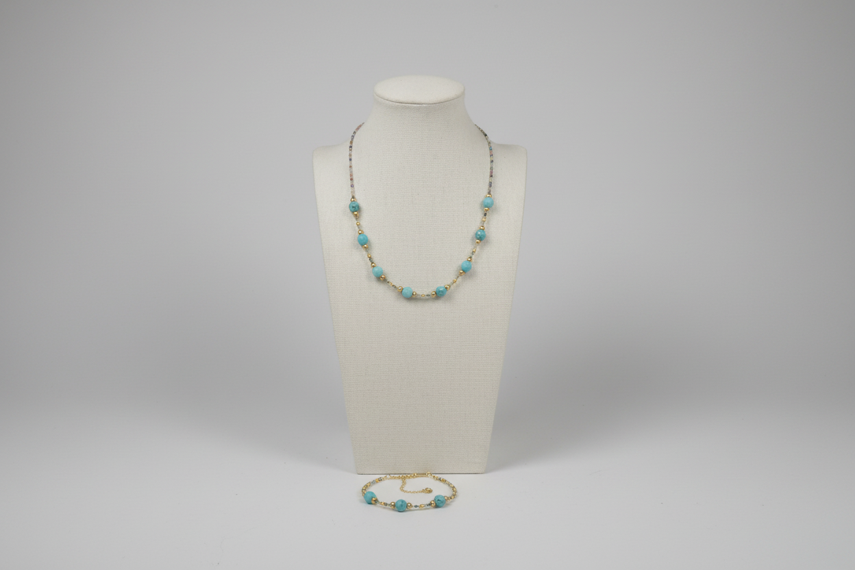Necklace with turquoise beads on a mannequin bust against a gray background
