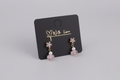 Pair of earrings on a black card with 'With Love' text, displayed on a wooden surface.