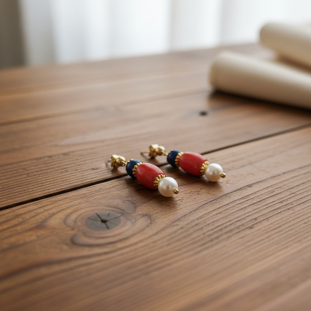 Pair of earrings with red, blue, and pearl beads on a gray background